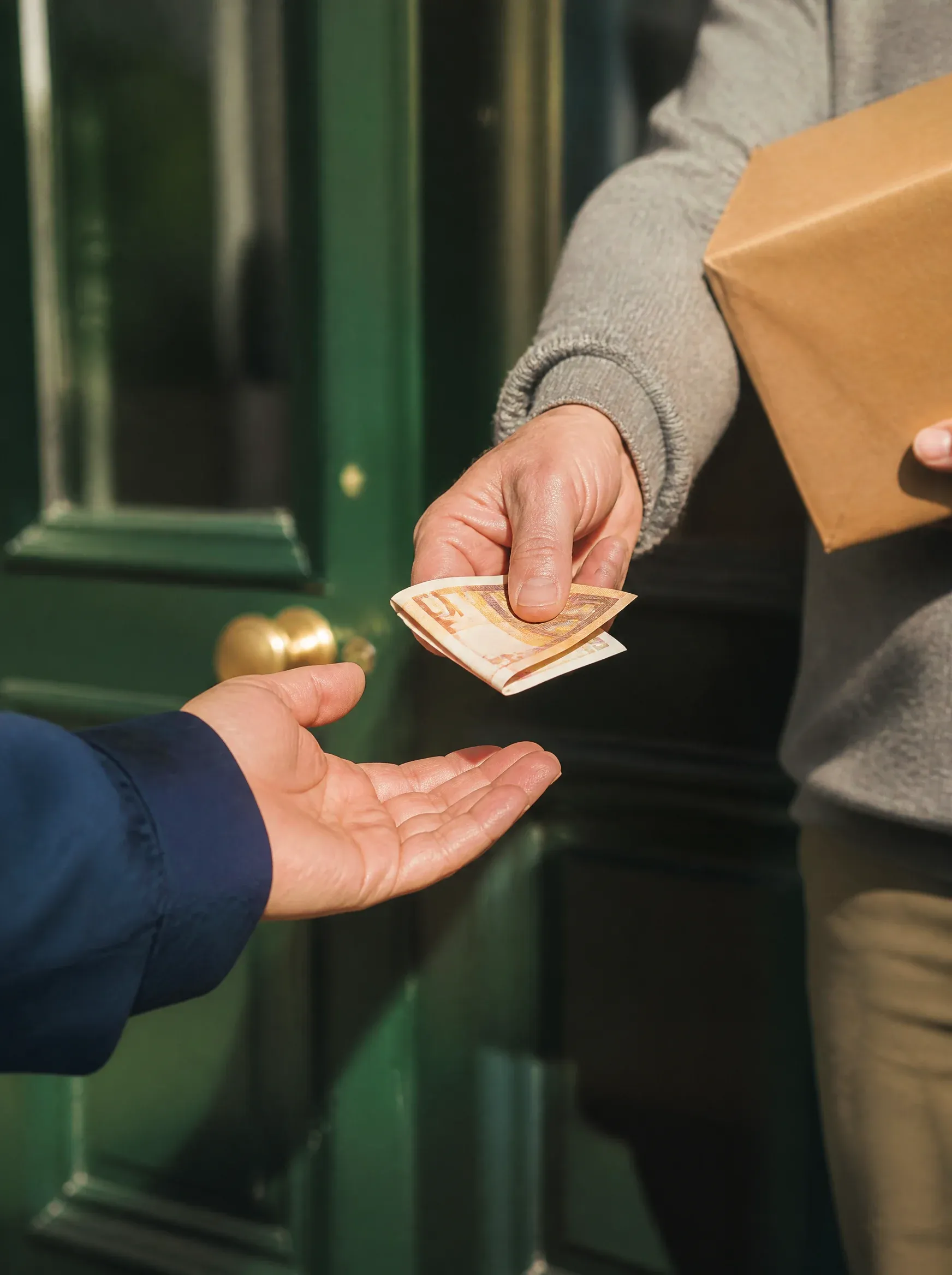 Un hombre entrega dinero al repartidor en el umbral de su casa
